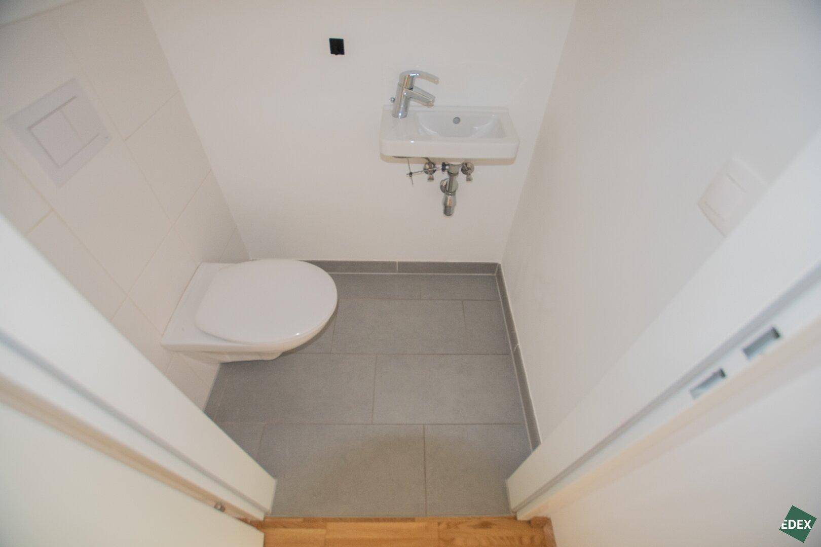 Kleines Gäste-WC mit wandhängendem WC und Handwaschbecken.