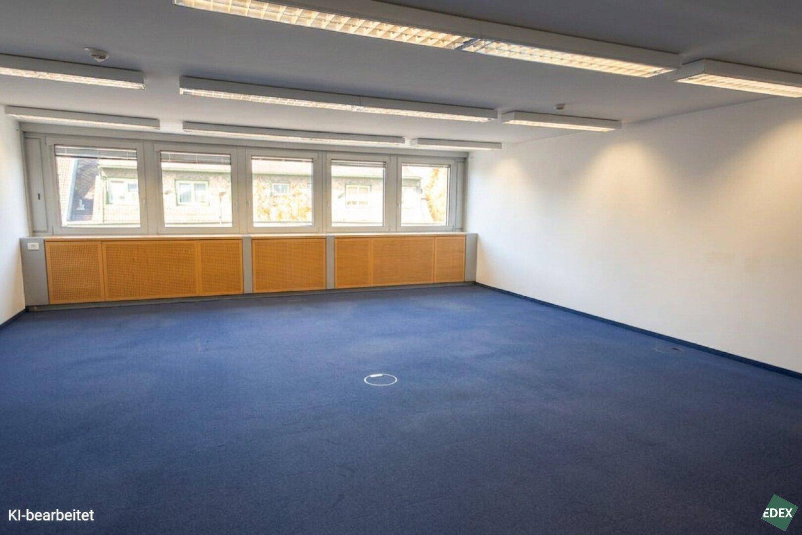 Großes, leeres Büro mit blauer Teppichauslage, breiter Fensterfront und Holzverkleidung.