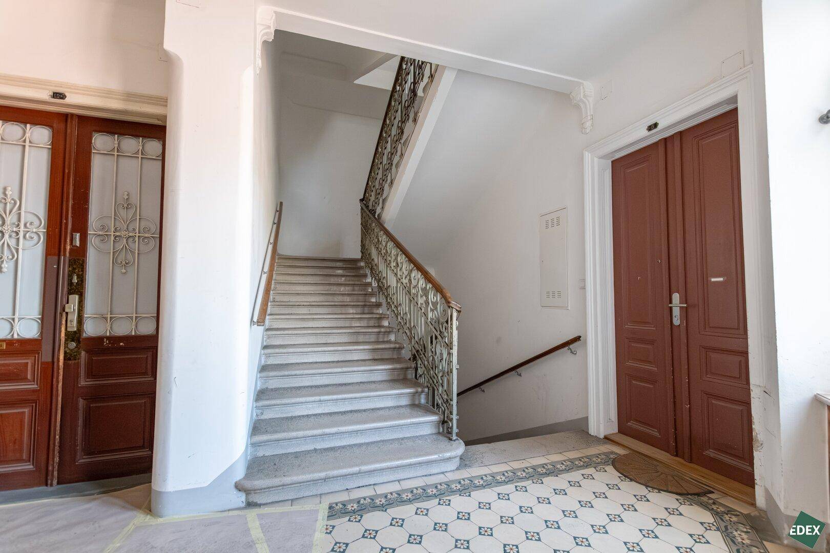 Repräsentatives Treppenhaus mit Marmorstufen, schmiedeeisernem Geländer und hohen Decken.