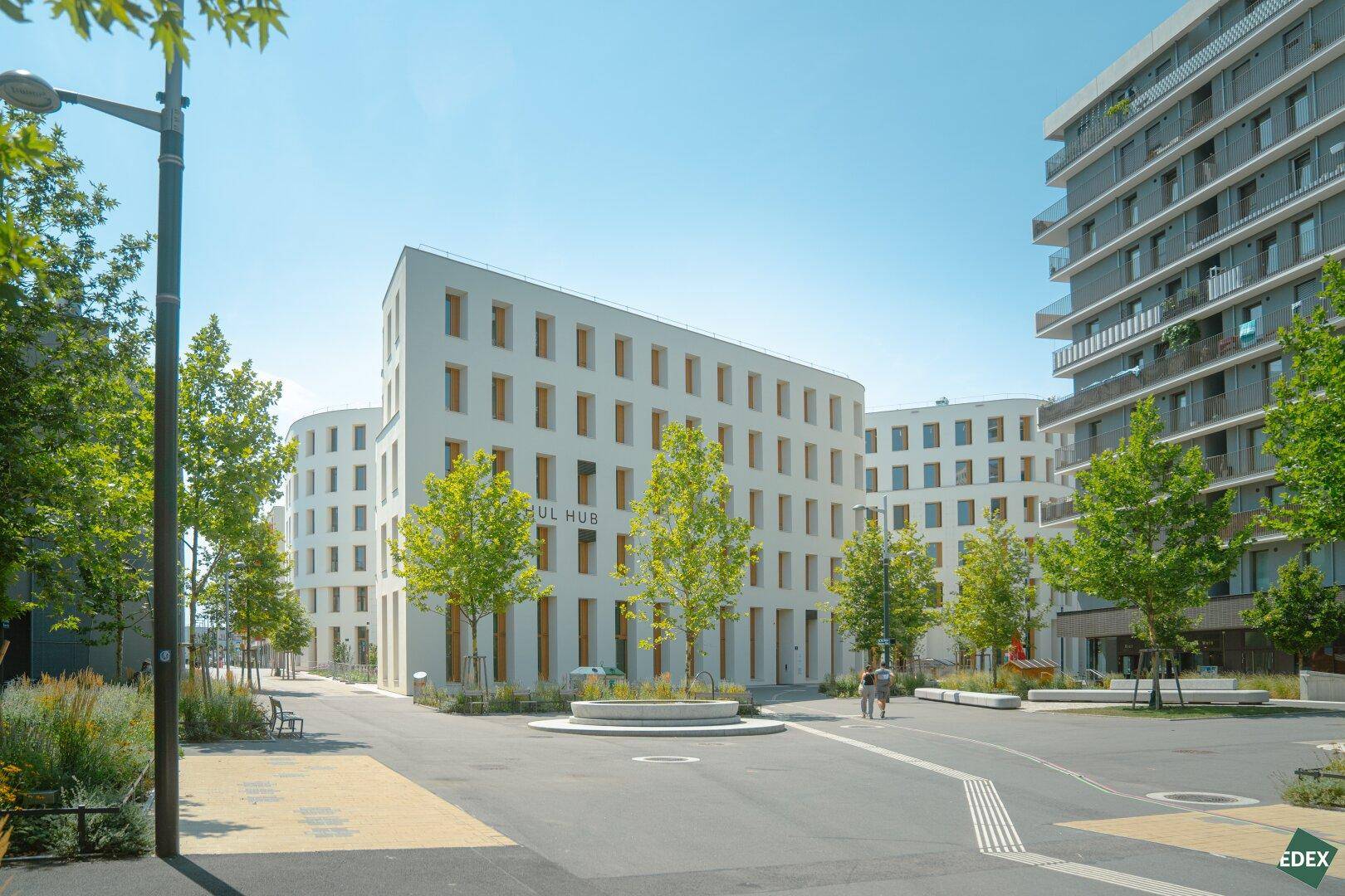 Weitläufige Ansicht eines modernen Gebäudekomplexes mit Grünflächen und klarem Himmel.