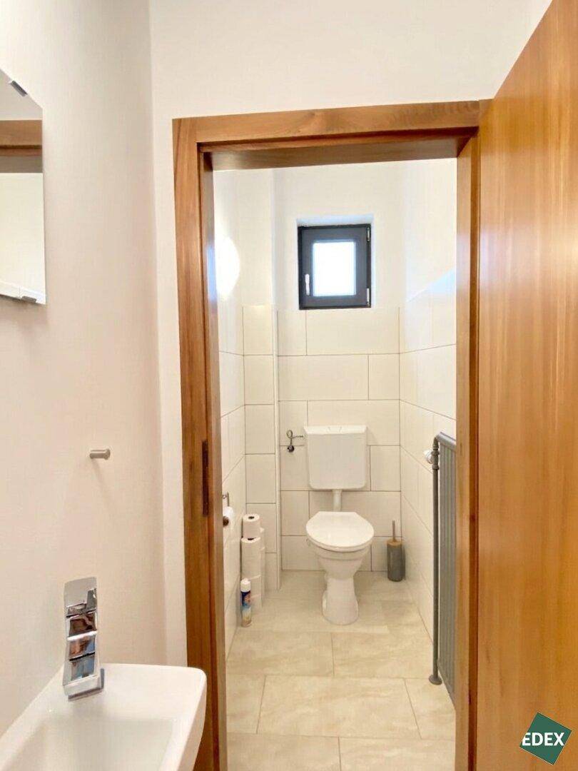 Separate Gästetoilette mit Fenster, WC und kleinem Waschbecken.