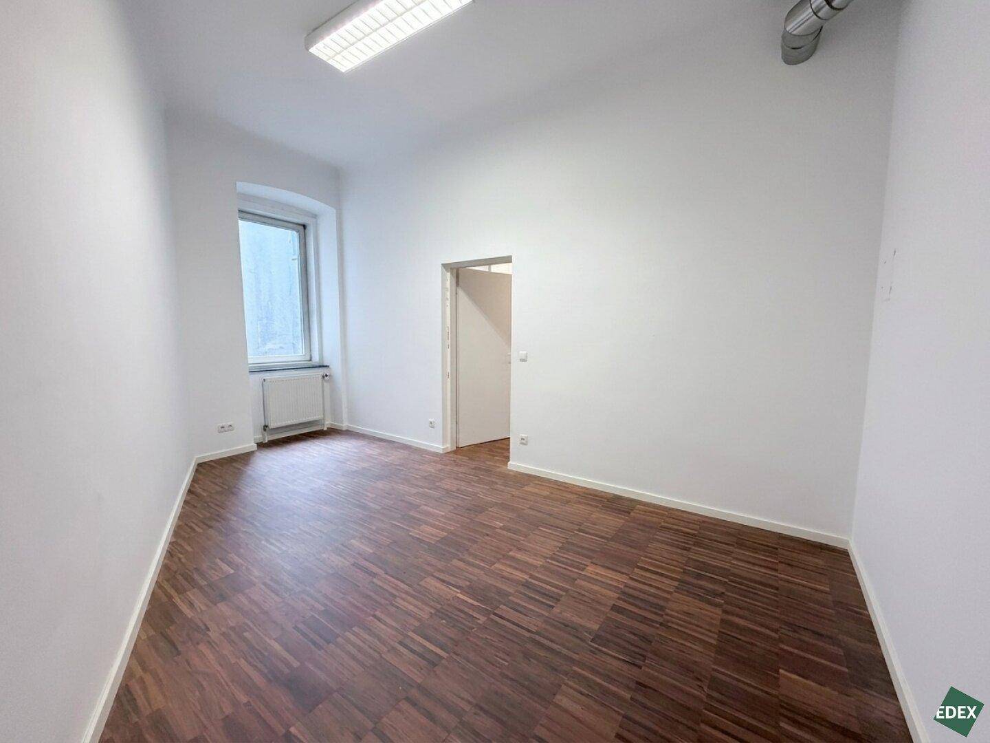 Heller Raum mit Parkettboden und einem Fenster, bietet eine ruhige Arbeitsumgebung.