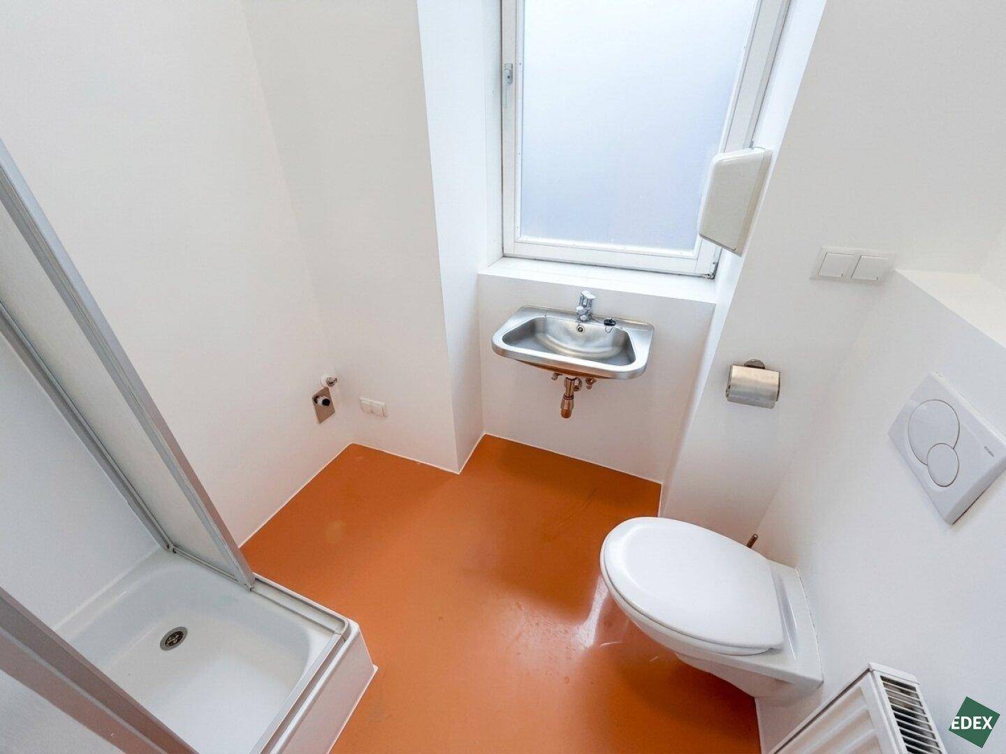 Helles Badezimmer mit Dusche, WC und Waschbecken, ausgestattet mit einem Fenster für Tageslicht.
