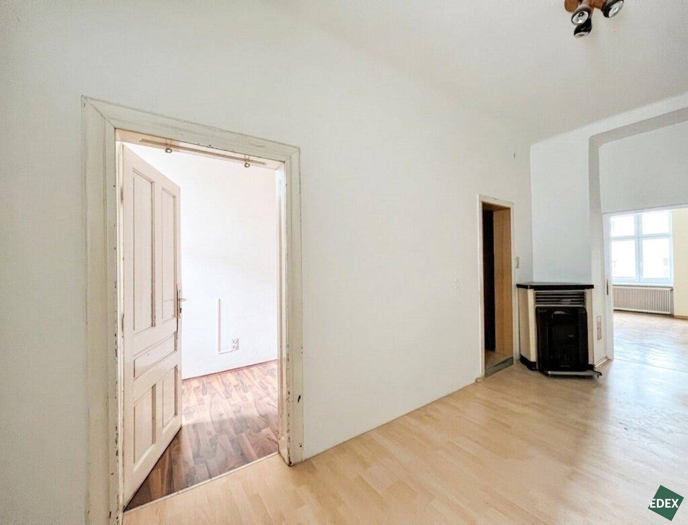 Helles Zimmer mit Laminatboden, weiß gestrichenen Wänden und einem Gasofen.