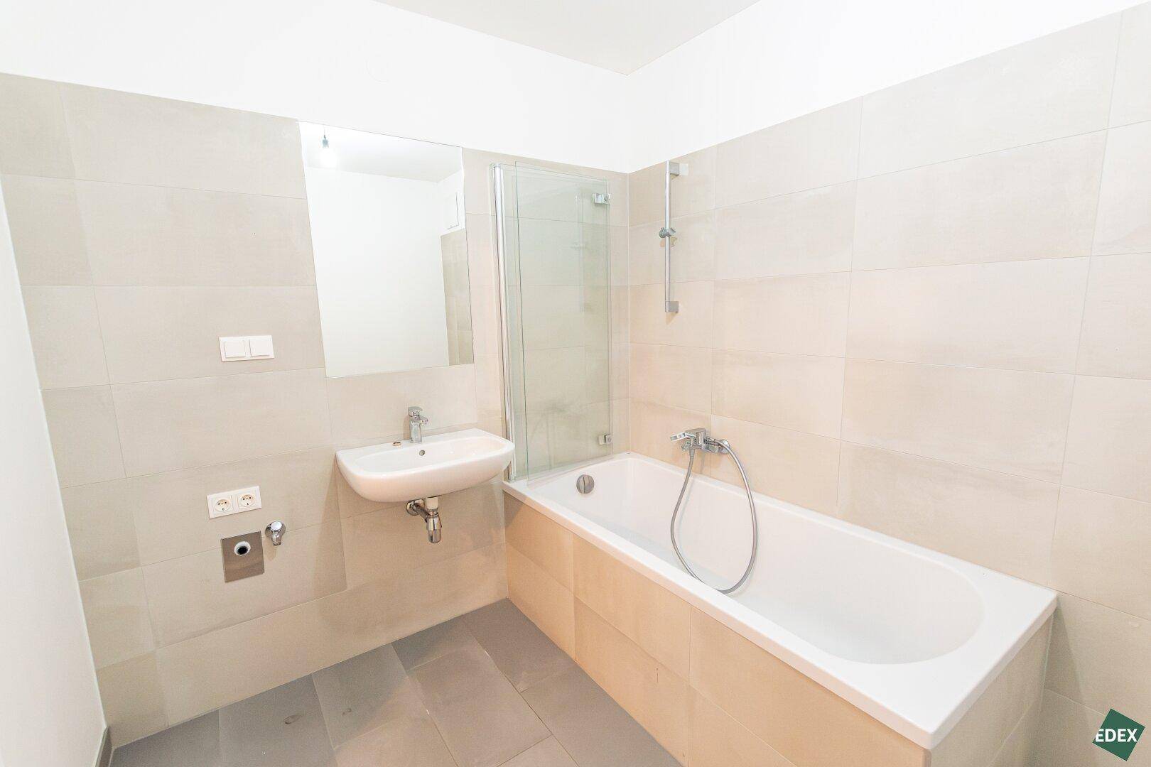 Modernes Badezimmer mit Badewanne, Waschbecken und hellen Fliesen, ausgestattet für Komfort.
