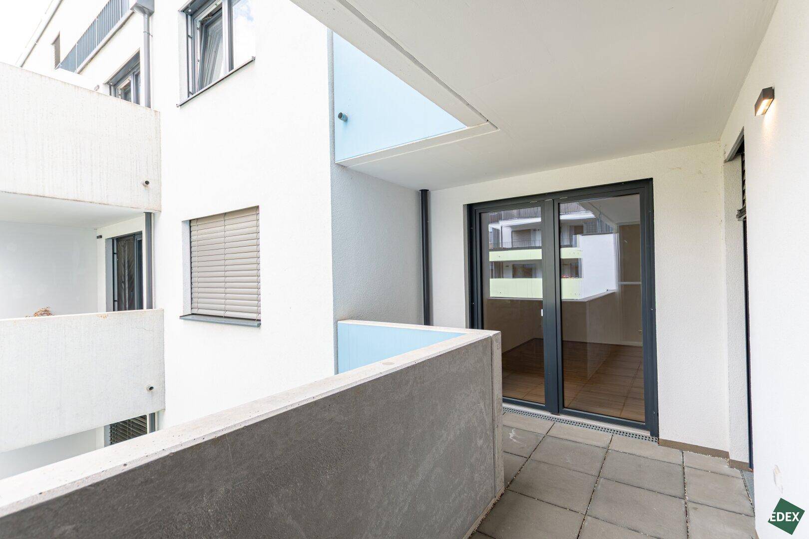 Geräumiger Balkon mit Fliesenboden und Blick auf den Innenhof, ideal für entspannte Stunden im Freien.