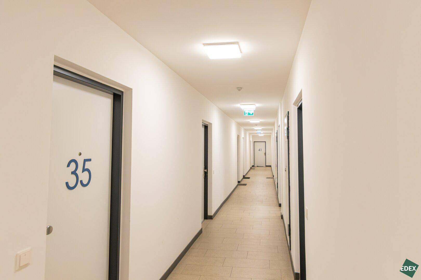 Heller Gemeinschaftsflur mit mehreren Wohnungstüren und Fliesenboden, gut beleuchtet.