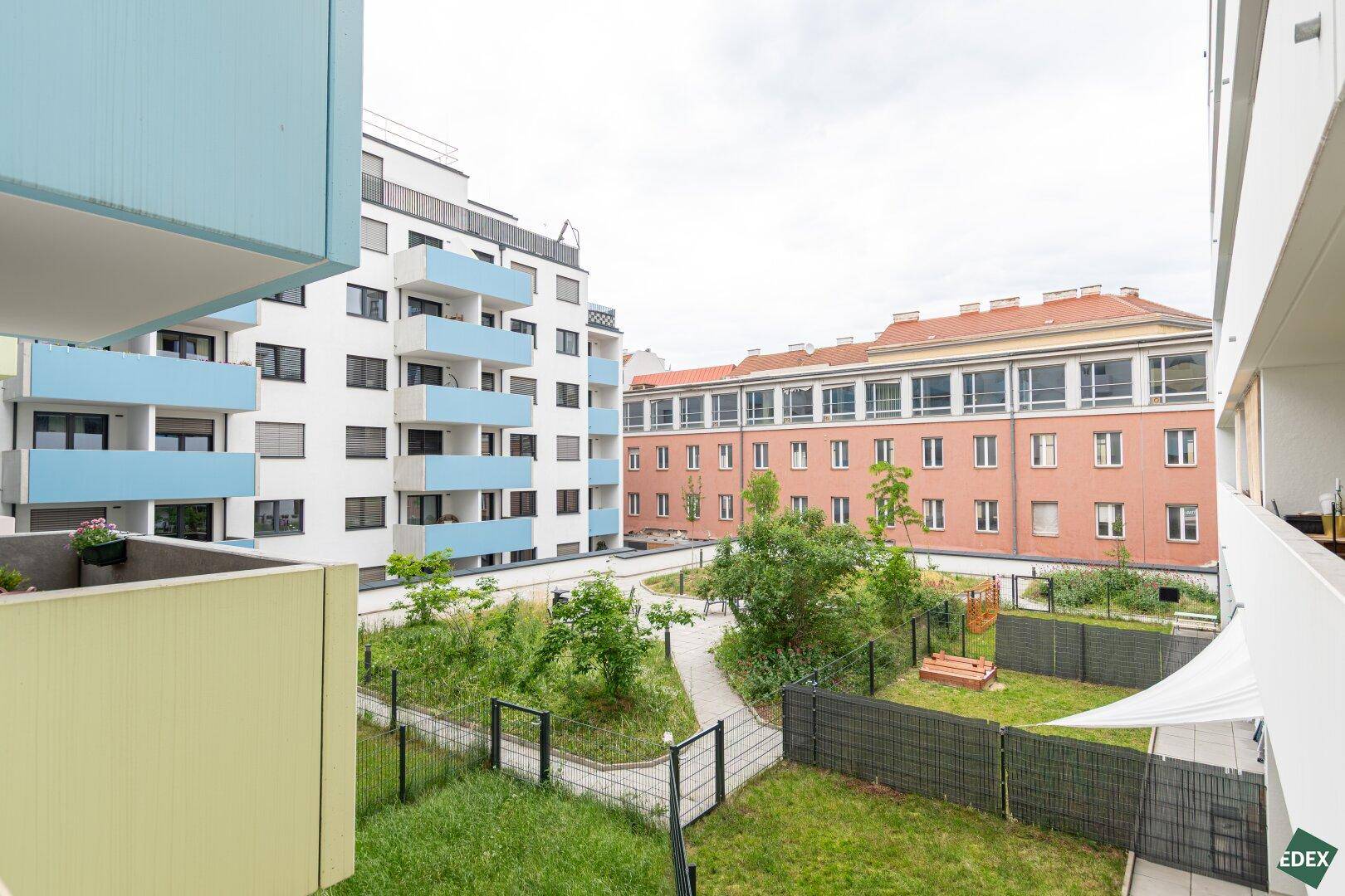 Blick auf den gepflegten Gemeinschaftsgarten mit Grünflächen und Spielbereich.