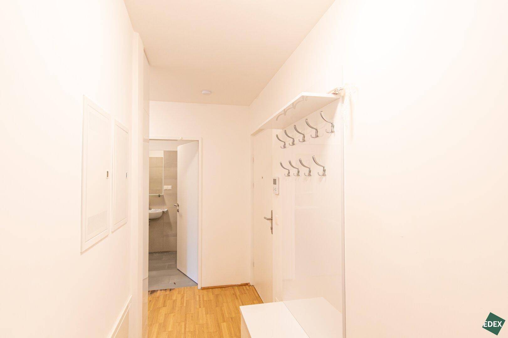 Heller Flur mit Garderobe und Zugang zu weiteren Räumen, inklusive Badezimmer.