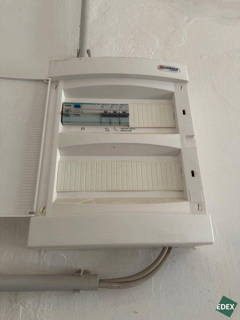 Nahaufnahme eines modernen Sicherungskastens an einer weißen Wand, der die Elektrik steuert.
