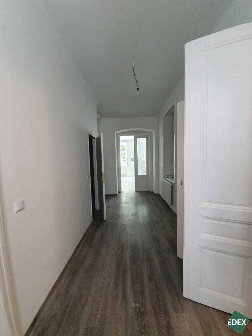 Langer Flur mit Laminatboden und mehreren Türen, der zu verschiedenen Bereichen der Wohnung führt.