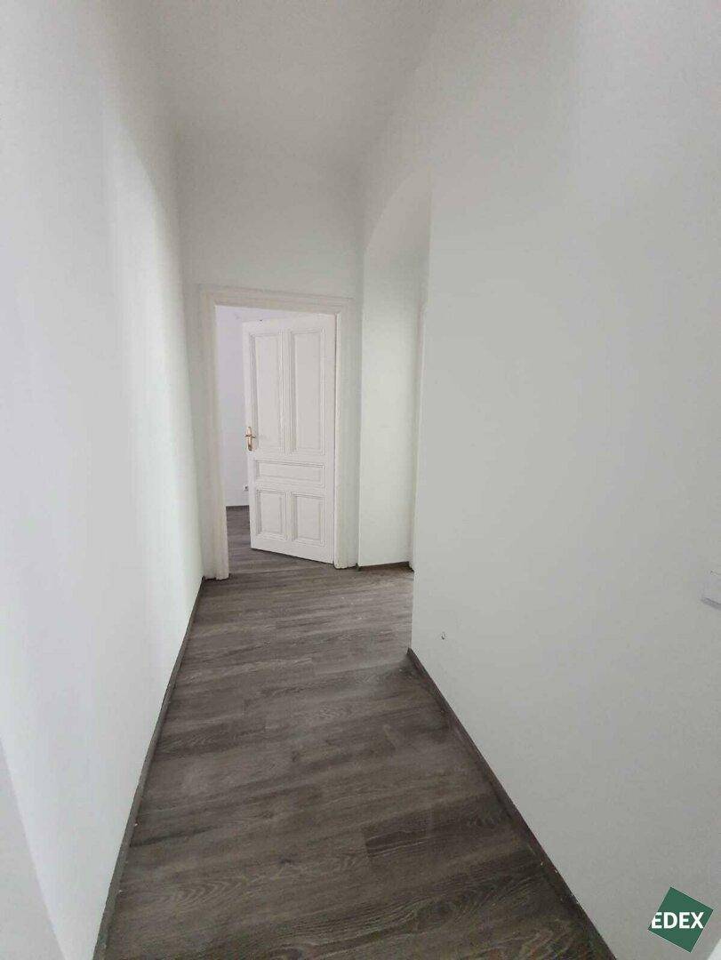Heller Flur mit Laminatboden und einer offenen Tür, die den Zugang zu weiteren Räumen ermöglicht.