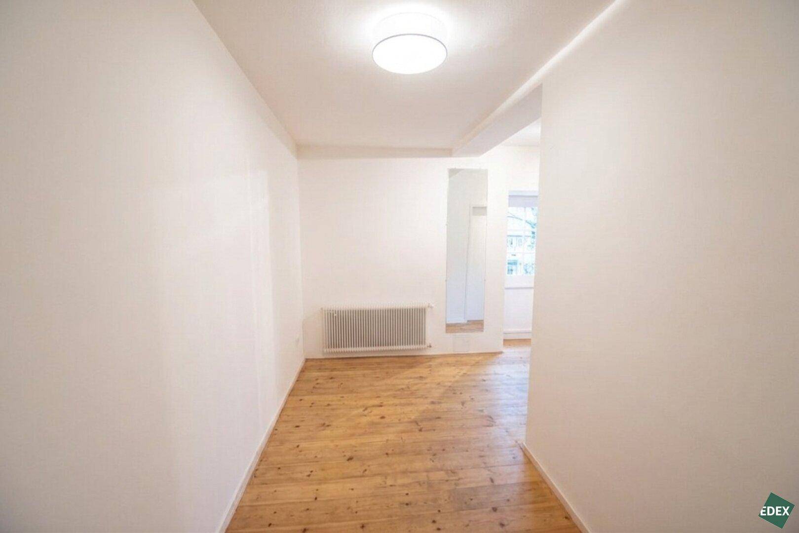 Heller Flur mit Holzdielenboden und einem großen Spiegel, der den Raum optisch erweitert.