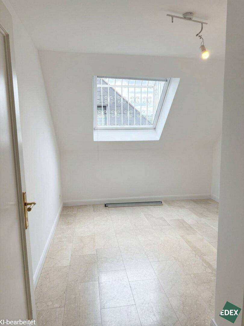 Helles Zimmer im Dachgeschoss mit Dachfenster und Fliesenboden.