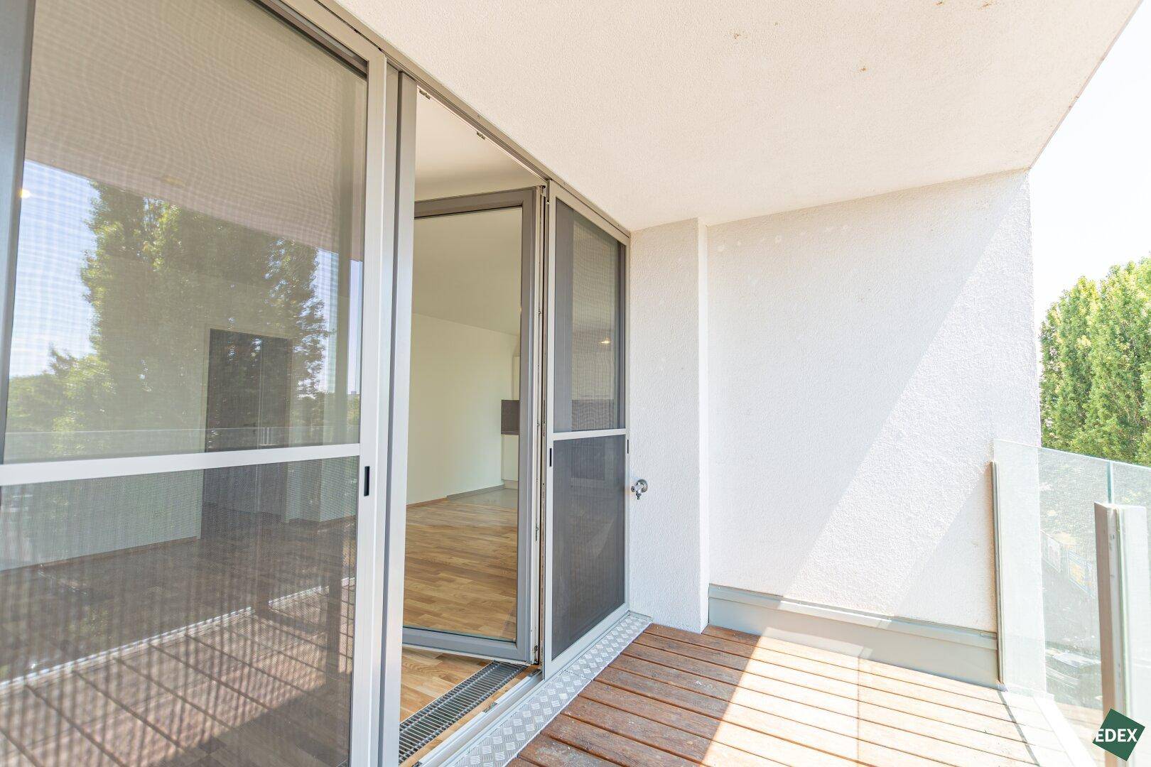 Geräumiger Balkon mit Holzboden und Zugang zum Innenraum, ideal für entspannte Stunden im Freien.