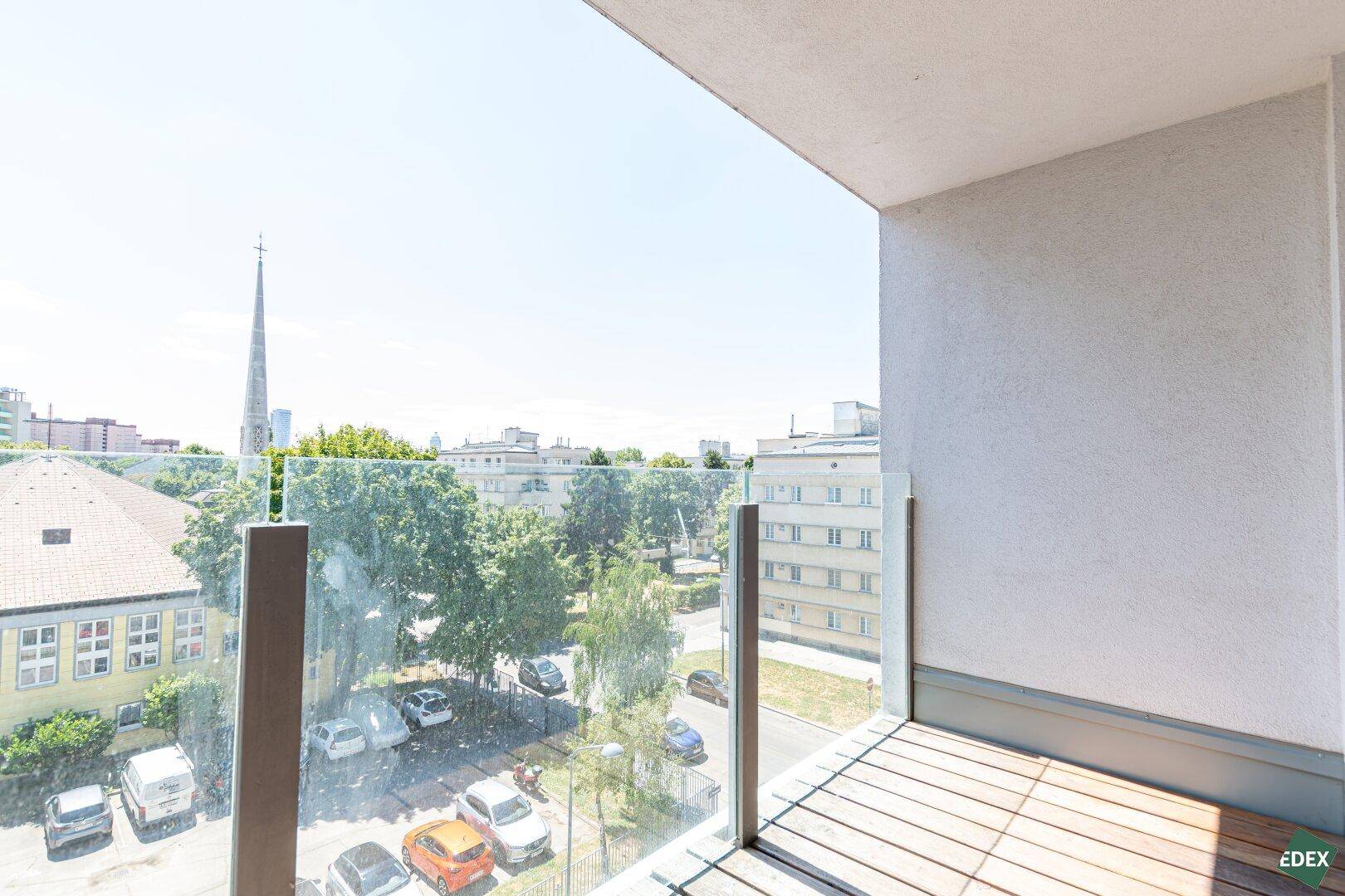 Balkon mit Glasbrüstung bietet einen weiten Blick über die Stadt und umliegende Gebäude.