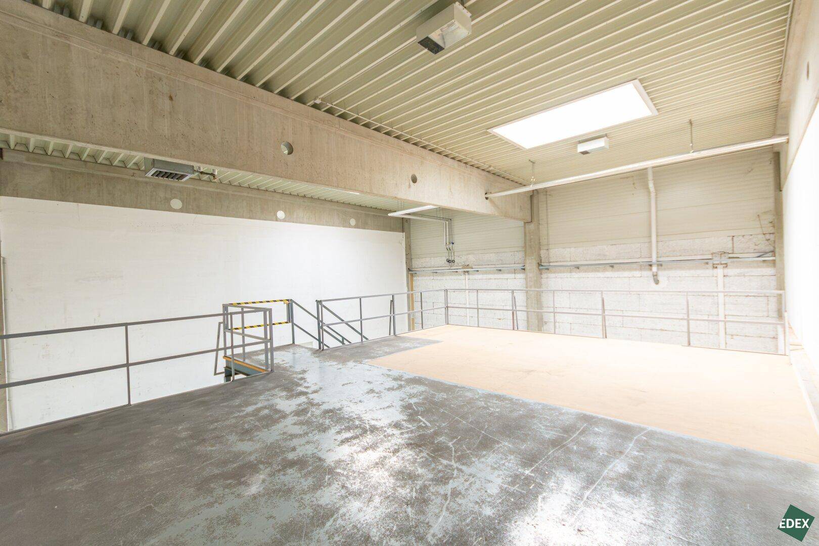 Geräumige Empore in einer Lagerhalle mit Betonstützen und Oberlichtern für Tageslicht.