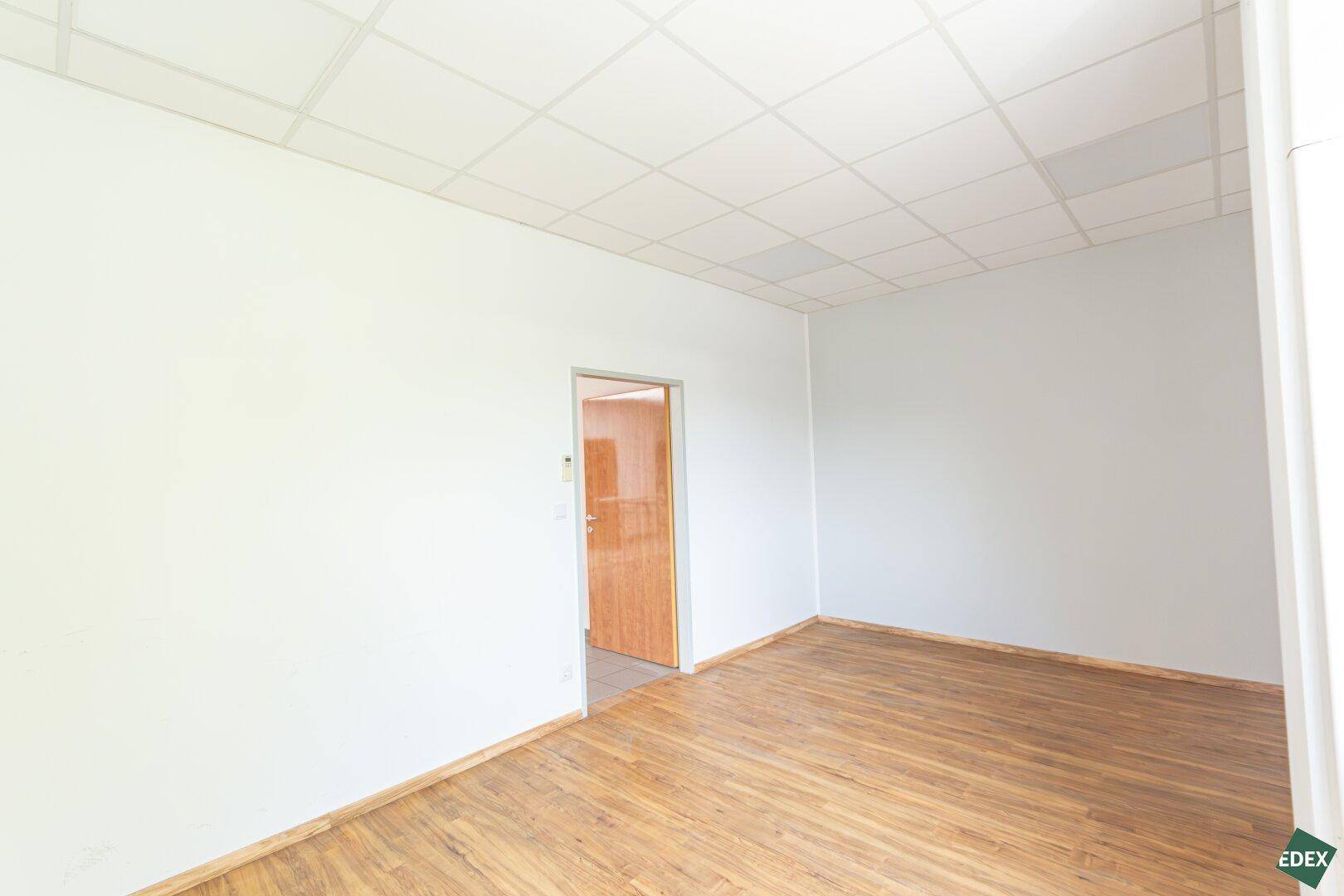 Heller Büroraum mit Holzboden und weißen Wänden, bereit zur individuellen Gestaltung.