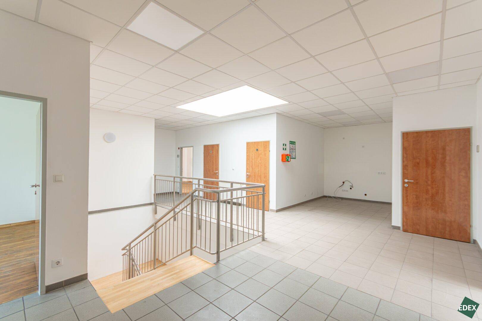 Heller Flur mit Fliesenboden und Treppe, die zu den oberen Etagen führt, mit mehreren Türen.
