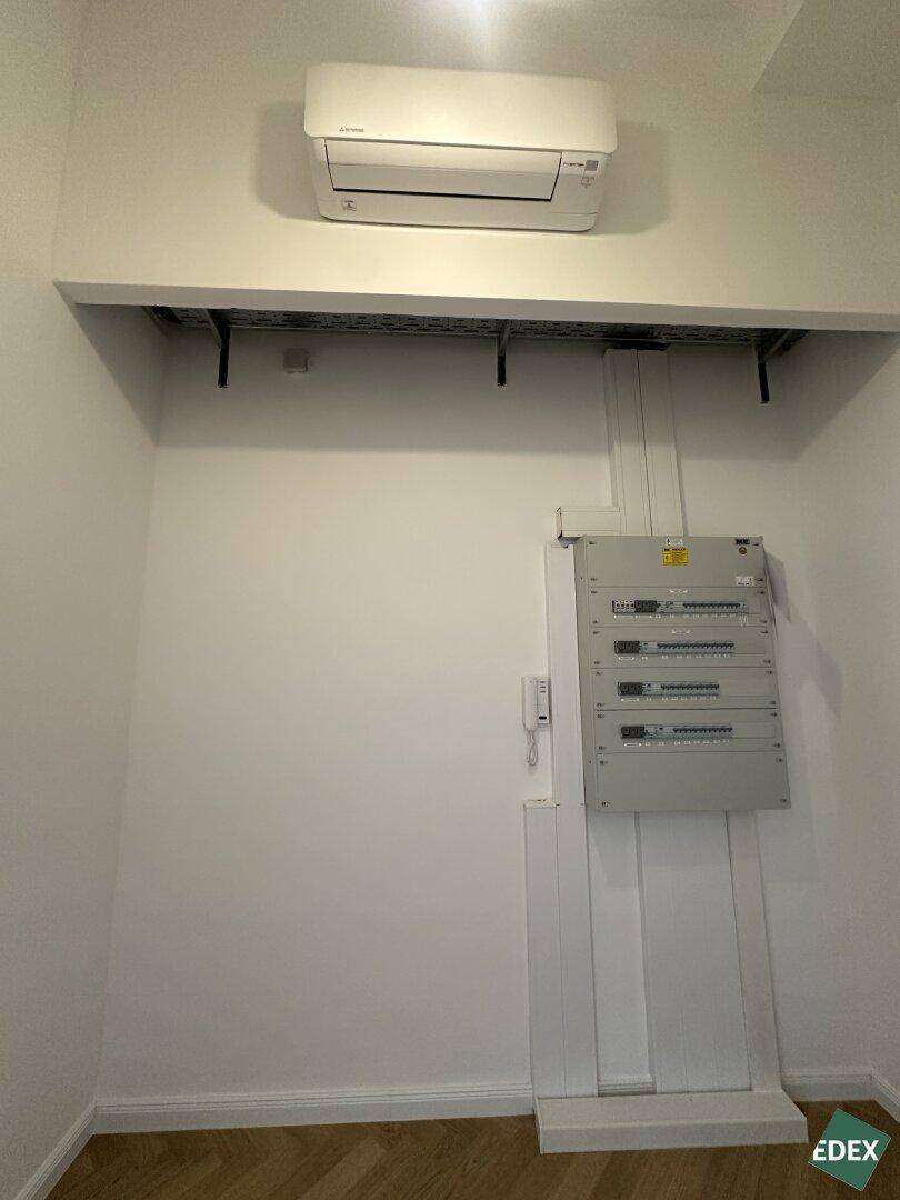 Technikraum mit Klimaanlage, Sicherungskasten und Kabeltrassen, funktional und gut organisiert.