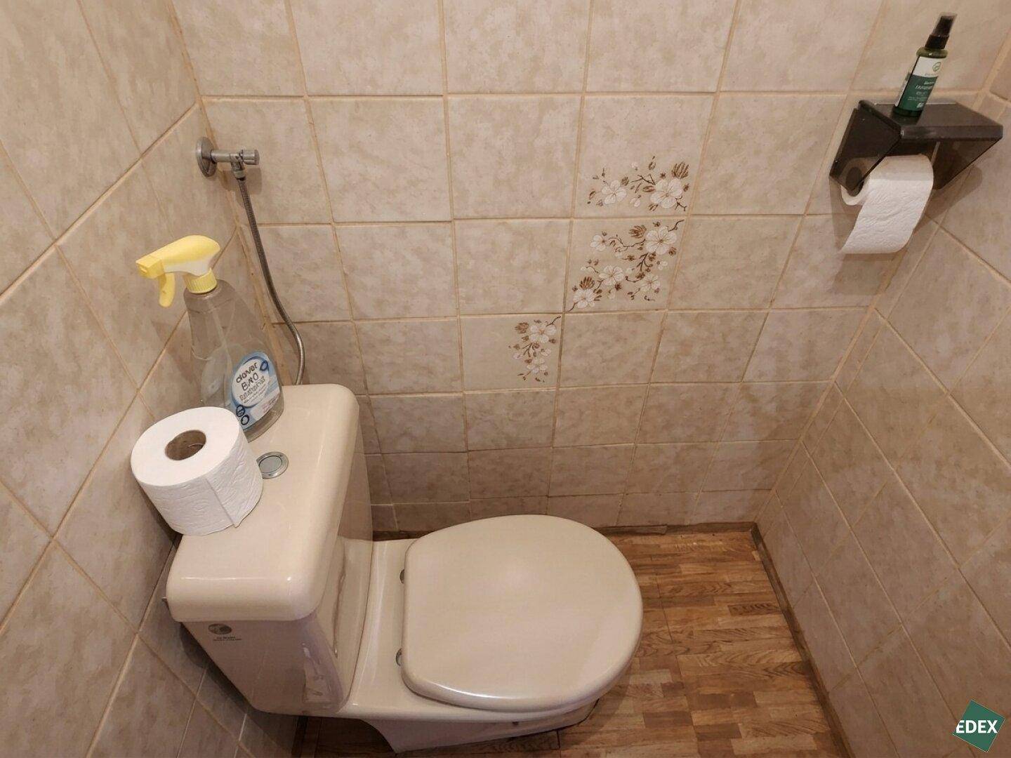 Kleines WC mit beigen Fliesen und einfacher Toilette, funktional und platzsparend.