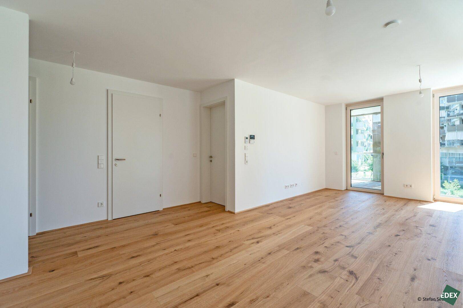 Geräumiger Flur mit Holzboden und Zugang zu weiteren Räumen sowie einem Balkon.