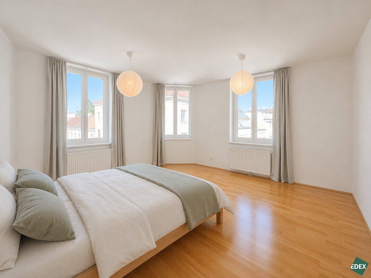 Geräumiges Schlafzimmer mit Holzboden, großem Bett und zwei Fenstern für viel Tageslicht.