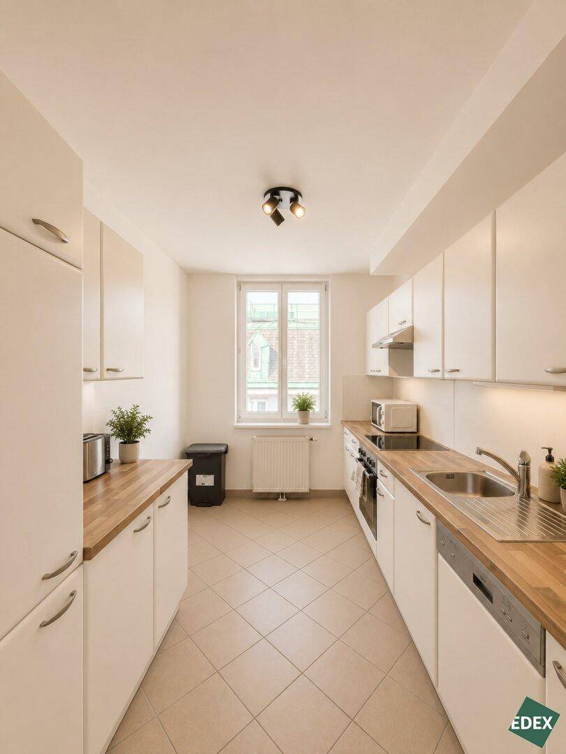 Funktionale Küche mit weißen Schränken, Holz-Arbeitsplatten und einem Fenster für Tageslicht.