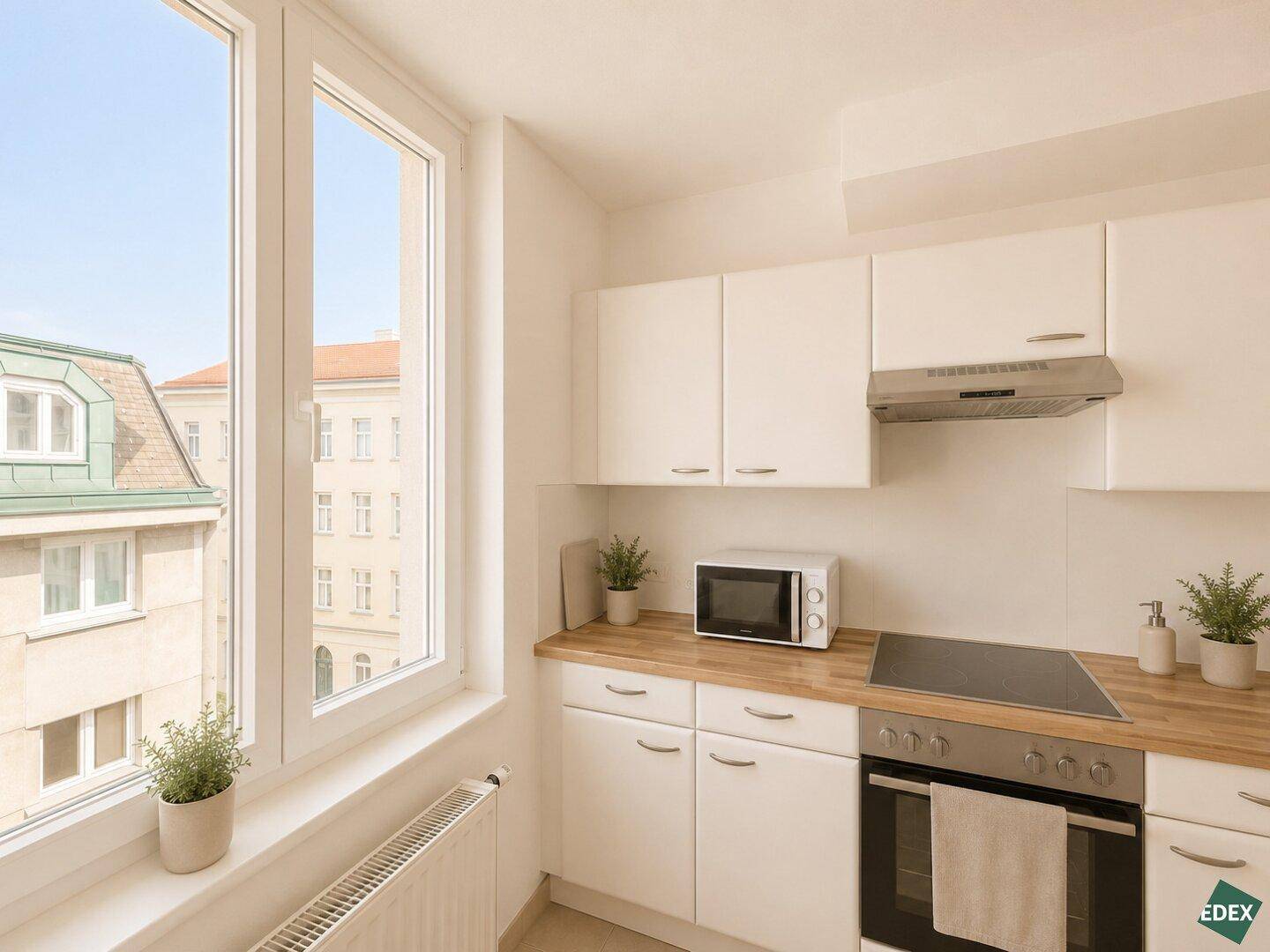 Helle Küche mit weißen Schränken, Holz-Arbeitsplatten und einem Fenster mit Stadtblick.