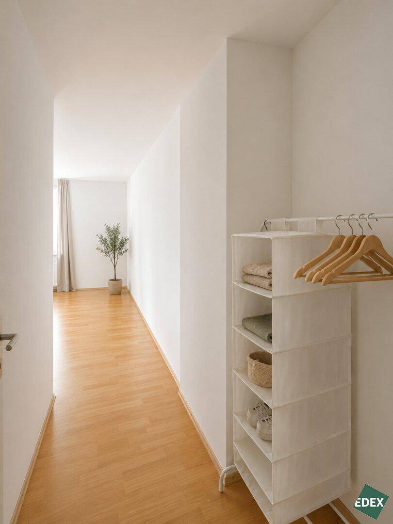 Langer, heller Flur mit Parkettboden, der zu einem Zimmer mit Fenster führt.