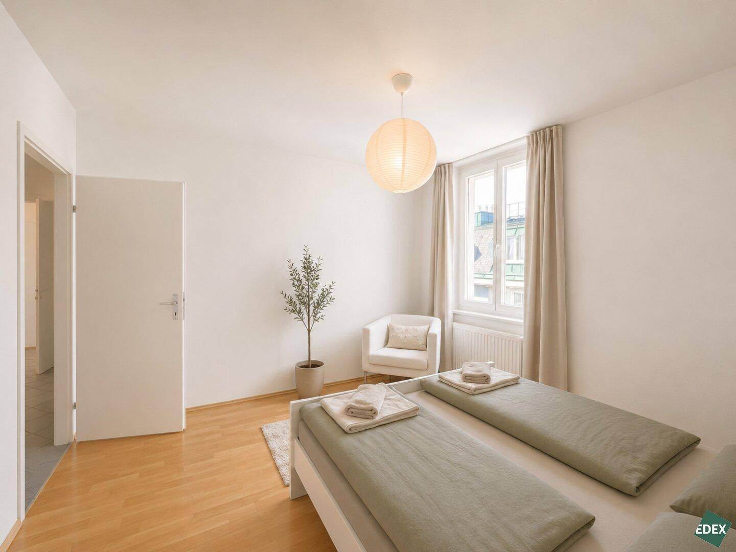Freundliches Schlafzimmer mit hellem Holzbett, Sessel und einem Fenster für natürliche Belichtung.