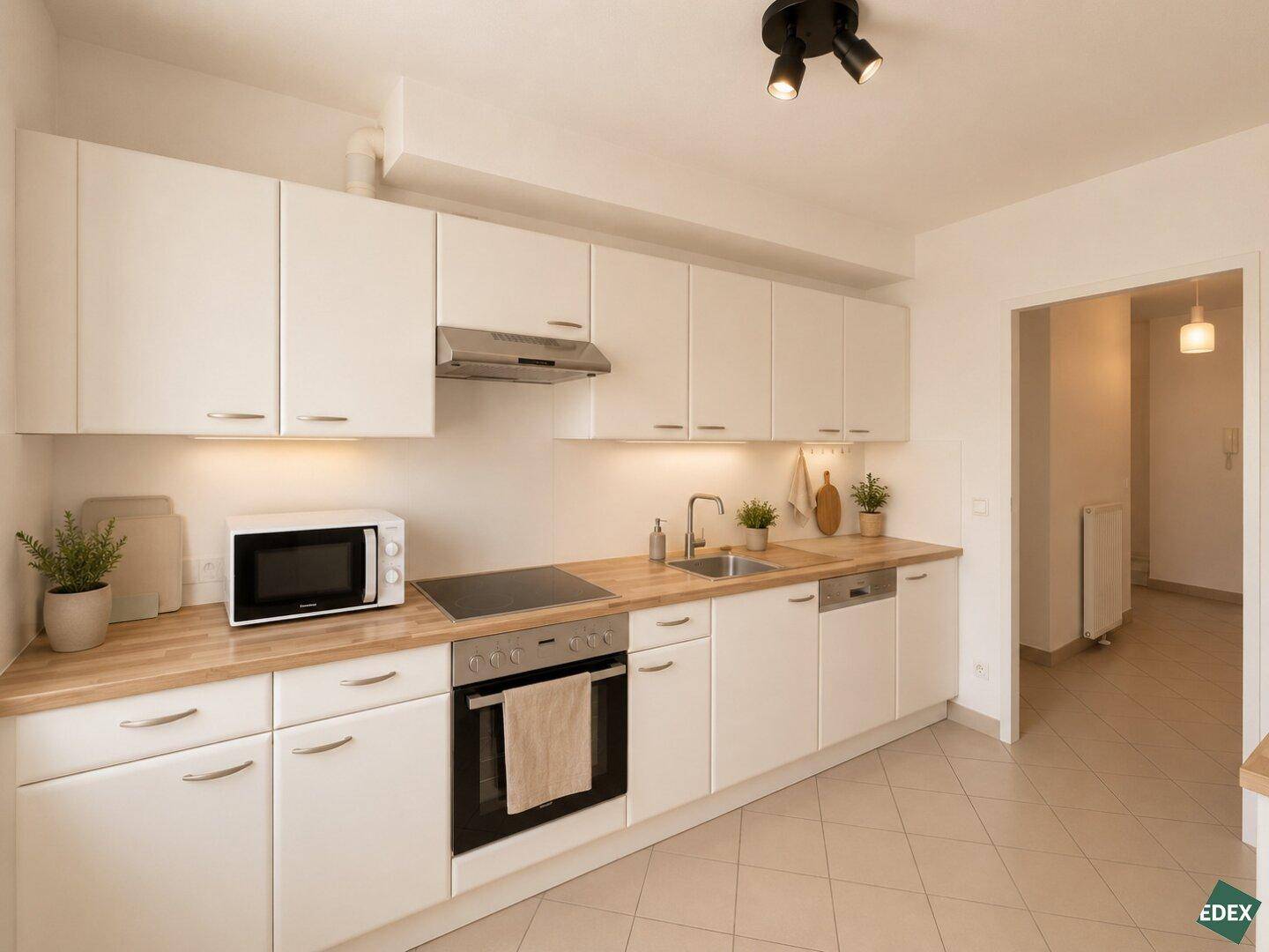 Moderne Einbauküche mit weißen Schränken, Holz-Arbeitsplatten und integrierten Geräten.