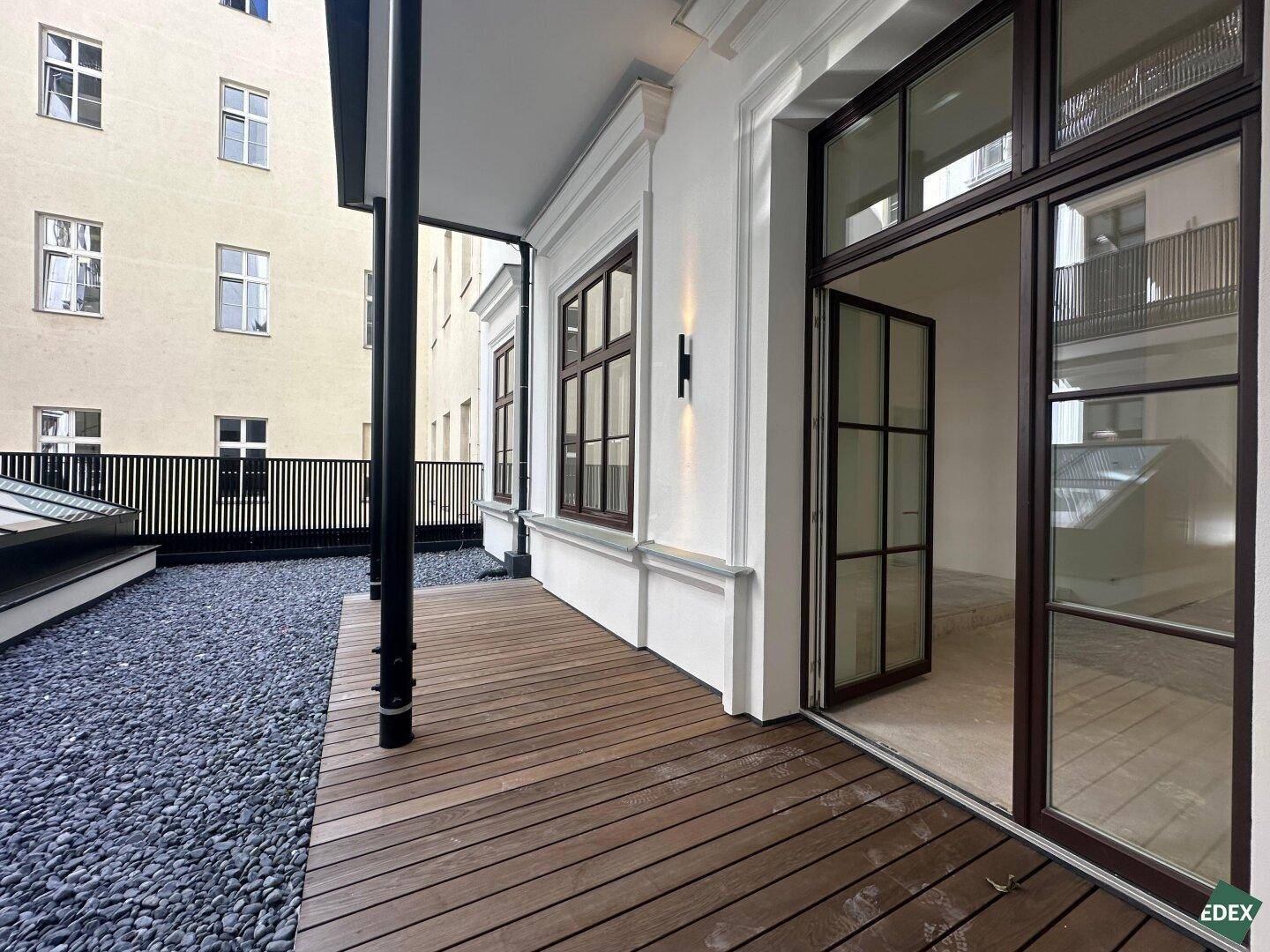 Überdachter Außenbereich mit Holzdeck und Blick auf den Innenhof, ideal für entspannte Stunden.