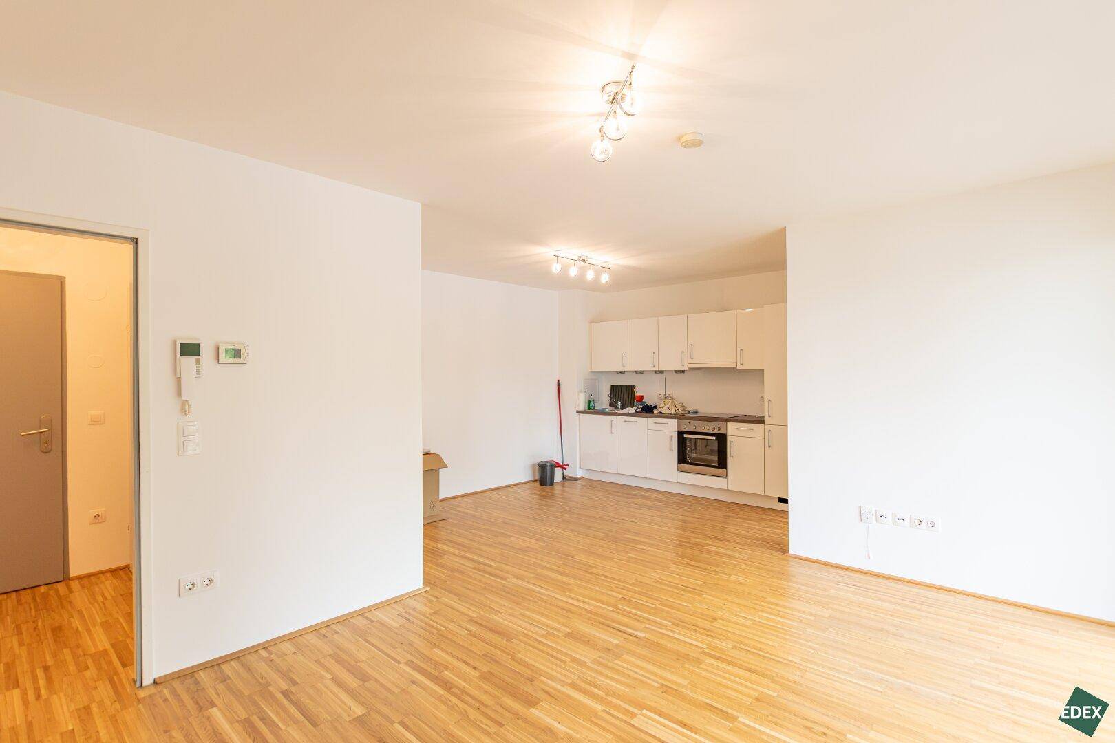 Geräumiger Wohnbereich mit offener Küche und Parkettboden, ideal für modernes Wohnen.