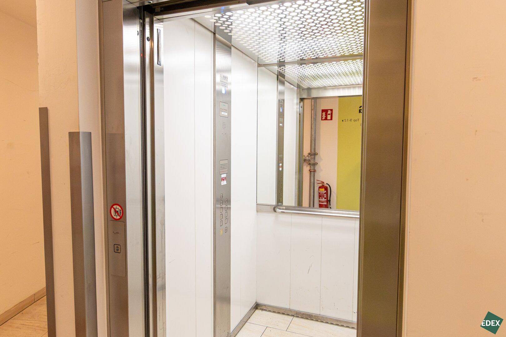 Moderner Aufzug mit Edelstahloberflächen und Spiegelflächen im Inneren des Gebäudes.