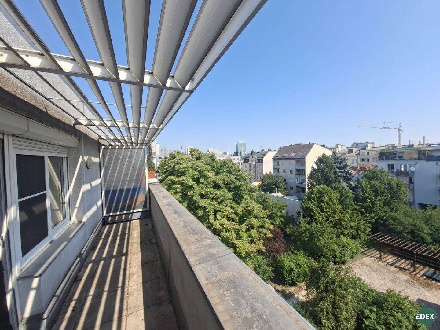 Panoramablick vom Balkon über die Stadtlandschaft und die umliegenden grünen Baumkronen.