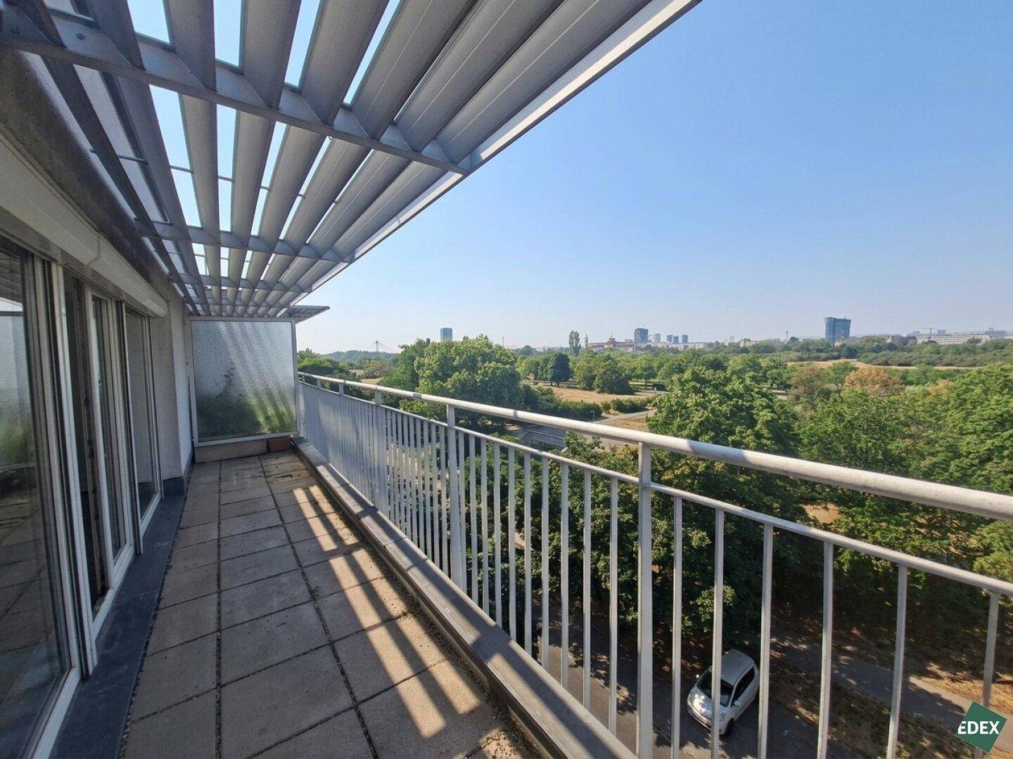 Geräumiger Balkon mit schützendem Lamellendach, ideal für Entspannung mit Blick ins Grüne.