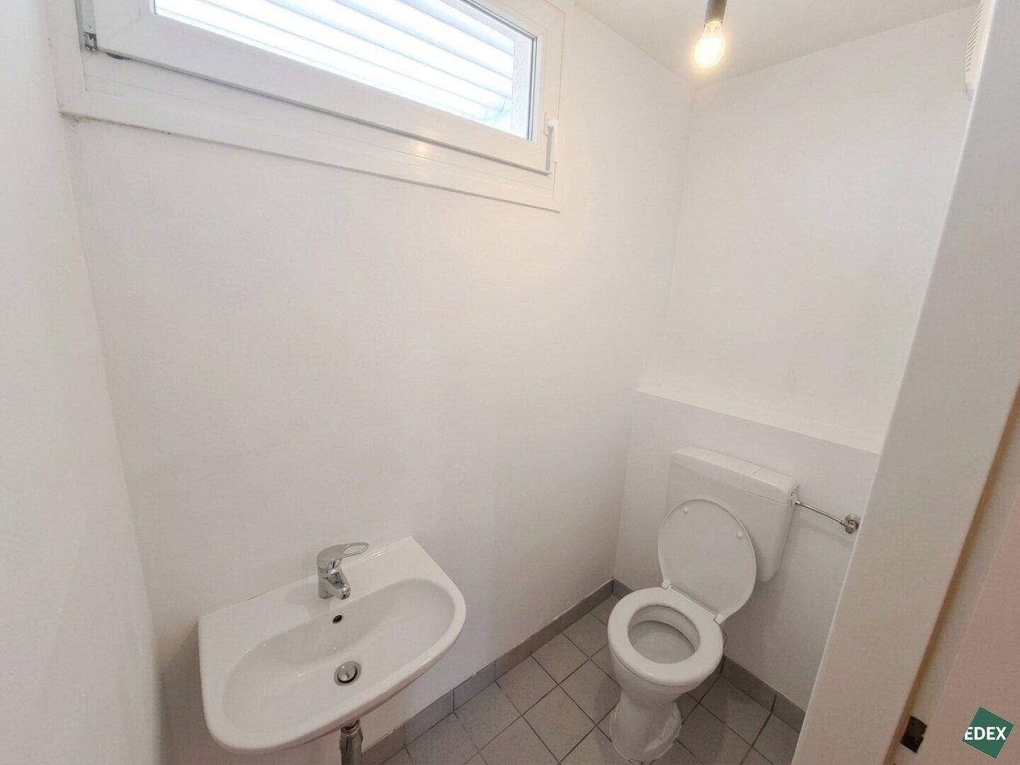 Kleines Gäste-WC mit Fenster, Waschbecken und Toilette, funktional und hell gestaltet.