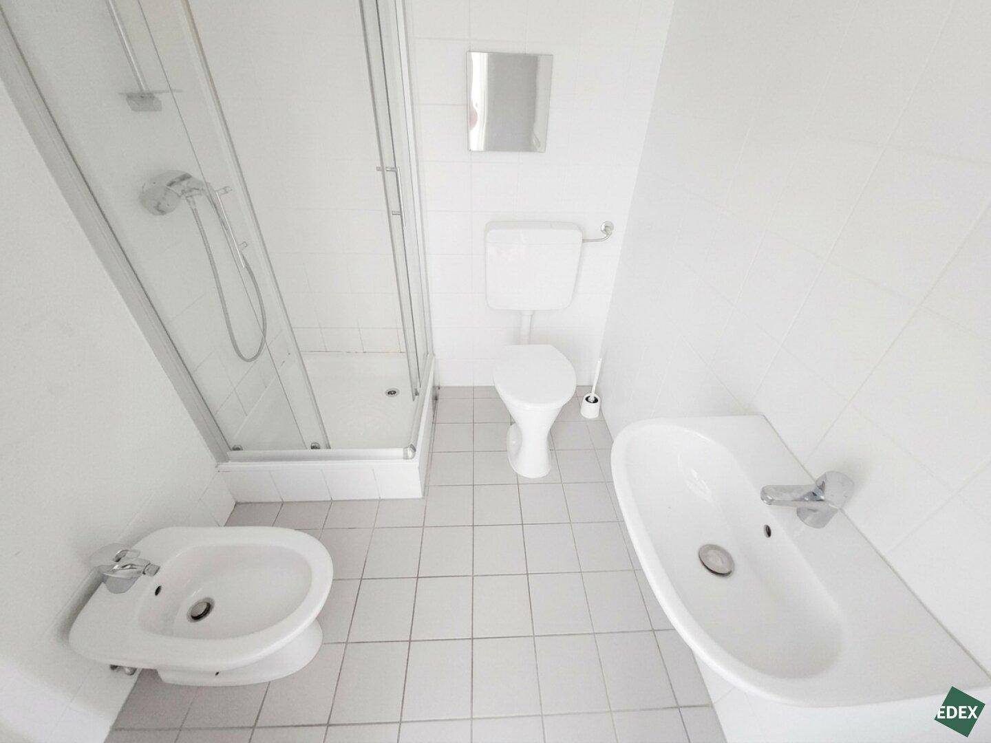 Funktionales Badezimmer mit Duschkabine, Toilette, Bidet und einem Waschbecken.