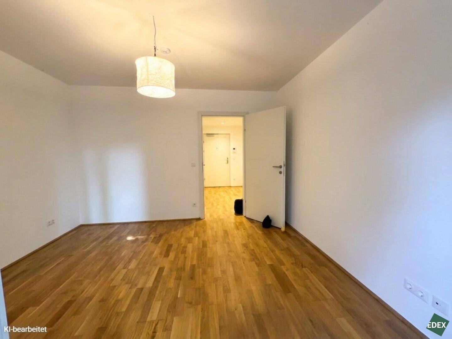 Geräumiges Zimmer mit Holzboden und weiß gestrichenen Wänden, bietet vielseitige Nutzungsmöglichkeiten.