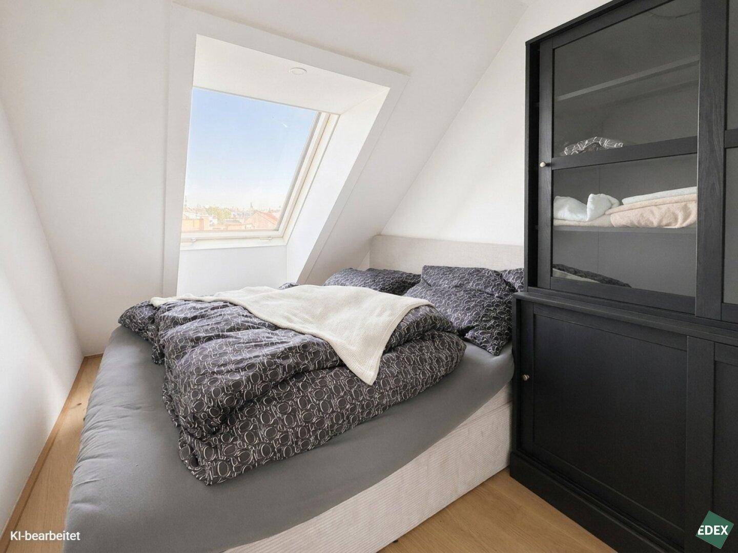 Gemütliches Schlafzimmer mit Dachschräge, Bett und großem Dachfenster für viel Licht.