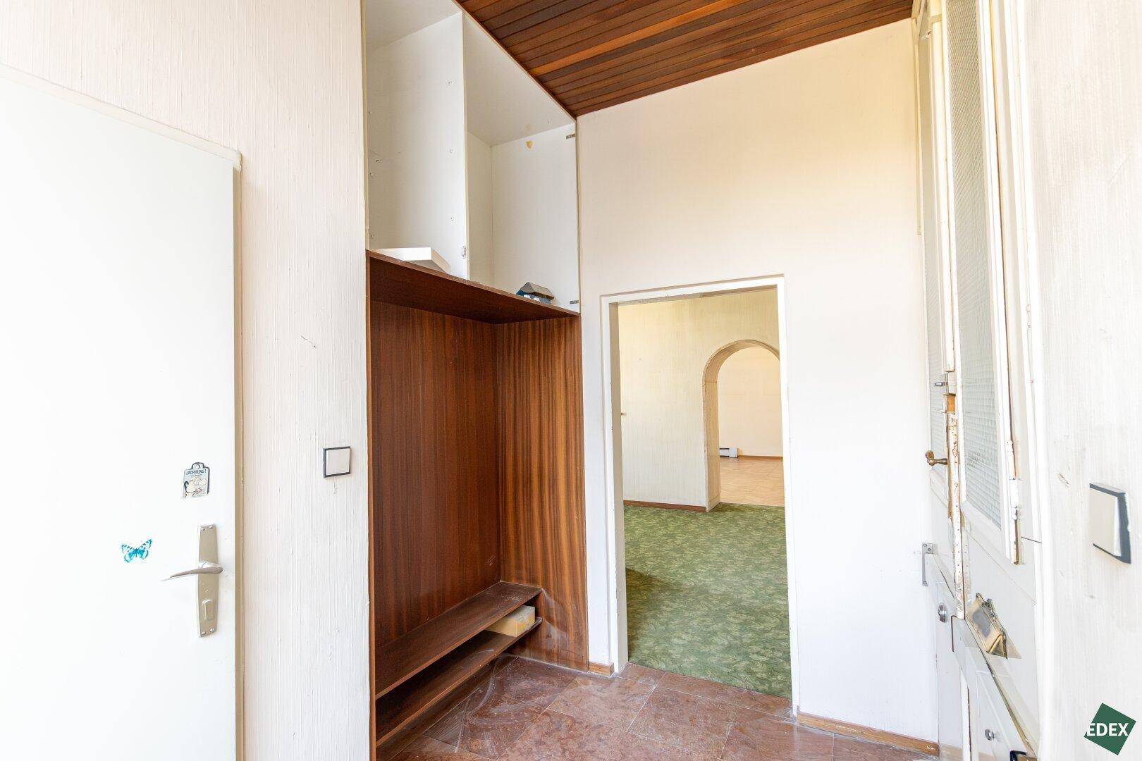 Flur mit Einbauschrank und Holzdecke, der zu weiteren Räumen führt.