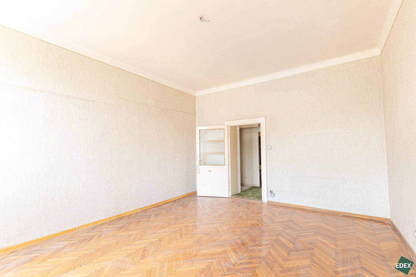 Geräumiges Zimmer mit Fischgrätparkett und einer Doppeltür, ideal für die Neugestaltung.