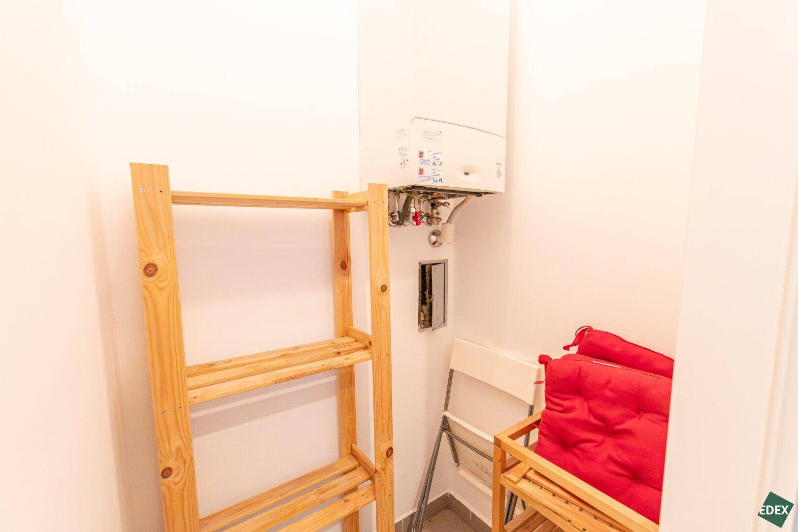 Kleiner Abstellraum mit Gastherme und Holzregal, ideal für zusätzlichen Stauraum.