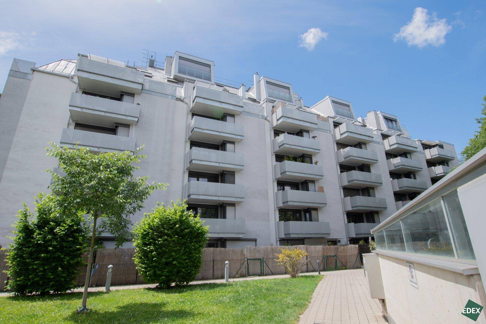 Ansicht eines modernen Wohnkomplexes mit Balkonen und gepflegter Außenanlage.