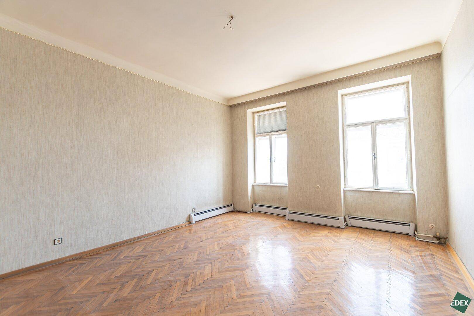 Großes Zimmer mit Fischgrätparkett und zwei Fenstern, ideal für eine moderne Neugestaltung.