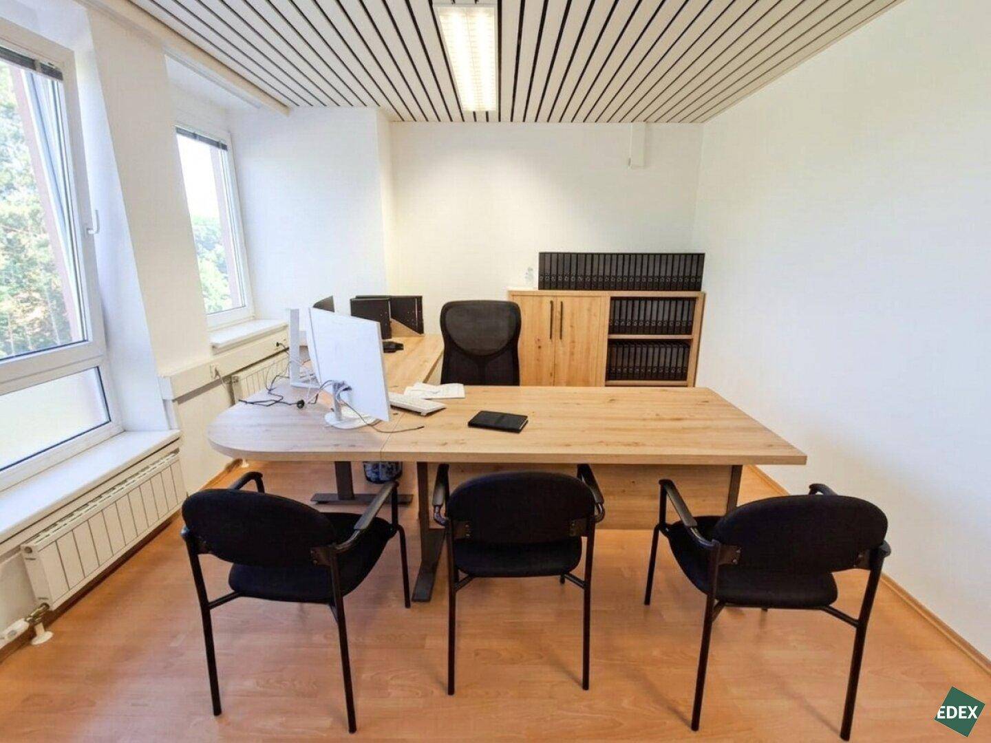 Arbeitsplatz in einem hellen Büro mit Holzschreibtisch, Bürostuhl und Stauraum.