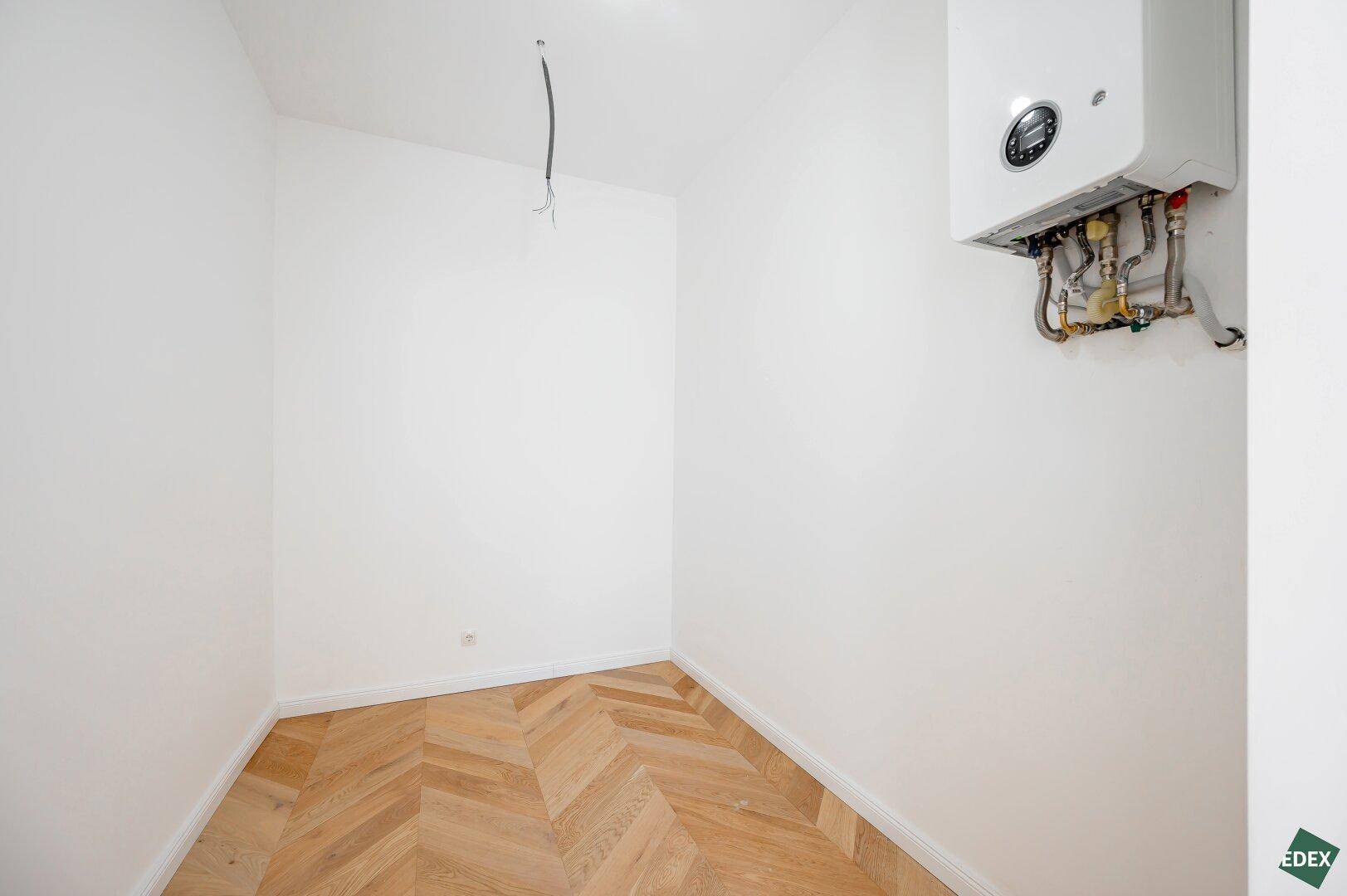 Kleiner Hauswirtschaftsraum mit Gastherme und Fischgrätparkettboden.