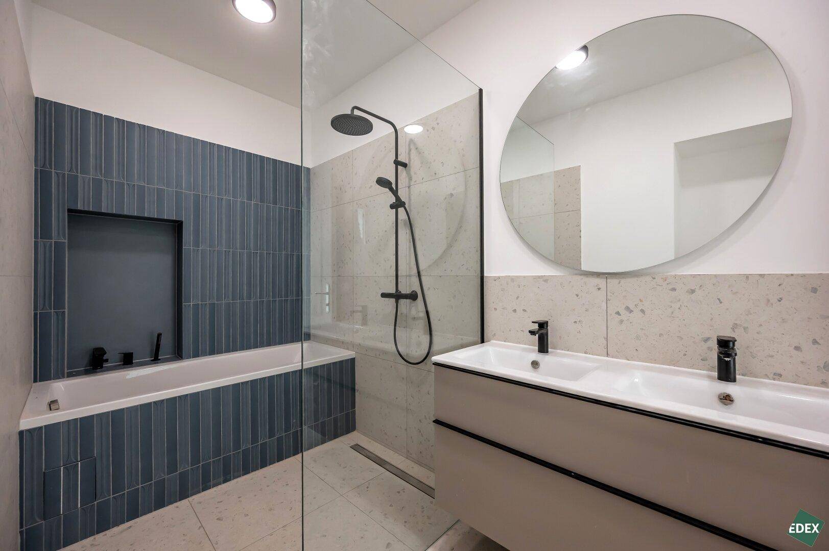 Elegantes Badezimmer mit Badewanne, Regendusche und Doppelwaschbecken, modern gefliest.
