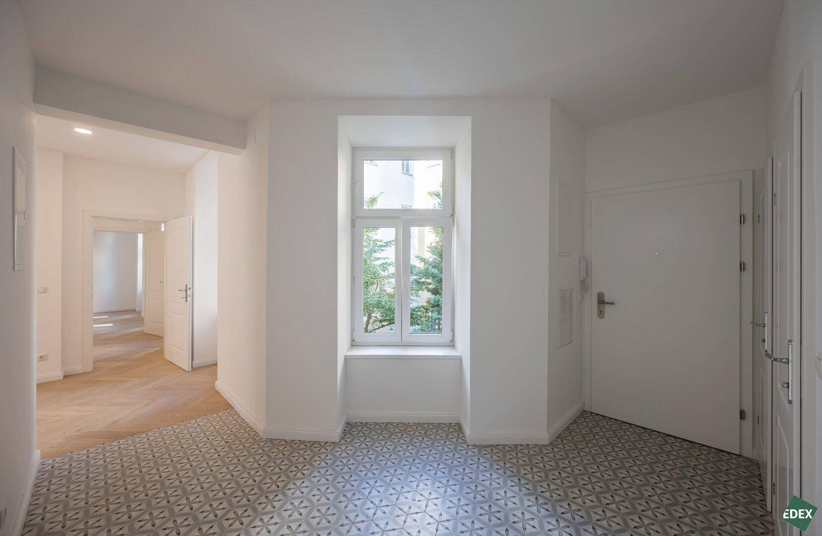 Eingangsbereich mit gemusterten Fliesen, Fenster und Zugang zu weiteren Räumen.